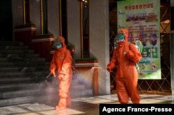 FILE - Workers spray disinfectant as part of preventative measures to curb the spread of the coronavirus at the Yokjon Department Store in Pyongyang, North Korea, Oct. 20, 2021.