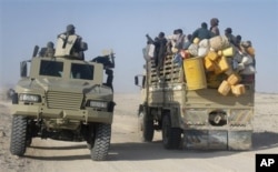 FILE - East African civilians depart in a truck, right, as AMISOM forces advance on al-Shabab-controlled region, Somalia, Sept. 4, 2012.