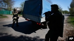 Pro-Russian armed militants prepare to inspect a truck near Slovyansk, eastern Ukraine, April 25, 2014.