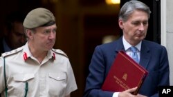 Britain's Defense Secretary Philip Hammond, right, and the Chief of Defense Staff Gen. Nick Houghton leave 10 Downing street following a national security meeting at Dow ning Street in London, Aug. 28, 2013.