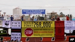 Cambodian non-governmental organization (NGOs) activists shout slogans during a protest against a proposed Don Sahong dam, in a tourist boat along the Tonle Sap river, in Phnom Penh, Cambodia, Sept. 11, 2014.