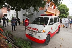 Sukarelawan bergabung dengan kerabat untuk berdoa di dekat ambulans yang membawa jenazah korban COVID-19, sebelum mengantarnya ke pemakaman untuk dimakamkan, di Bekasi di pinggiran Jakarta, 11 Juli 2021. (AP)