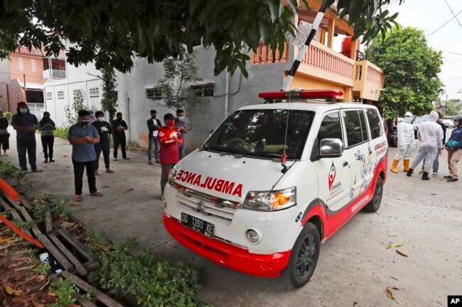 Sukarelawan bergabung dengan kerabat untuk berdoa di dekat ambulans yang membawa jenazah korban COVID-19, sebelum mengantarnya ke pemakaman untuk dimakamkan, di Bekasi di pinggiran Jakarta, 11 Juli 2021. (AP)