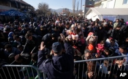 Serbian police officer attempt to organize migrants queuing to get registered at a refugee center in the southern Serbian town of Presevo, Nov. 16, 2015.