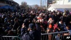 Serbian police officer attempt to organise migrants queuing to get registered at a refugee center in the southern Serbian town of Presevo, Monday, Nov. 16, 2015. 