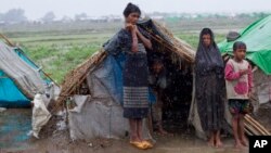 FILE - Internally displaced Rohingya stand outside their makeshift tent in a camp in Sittwe in Myanmar's northwestern Rakhine state in 2013.