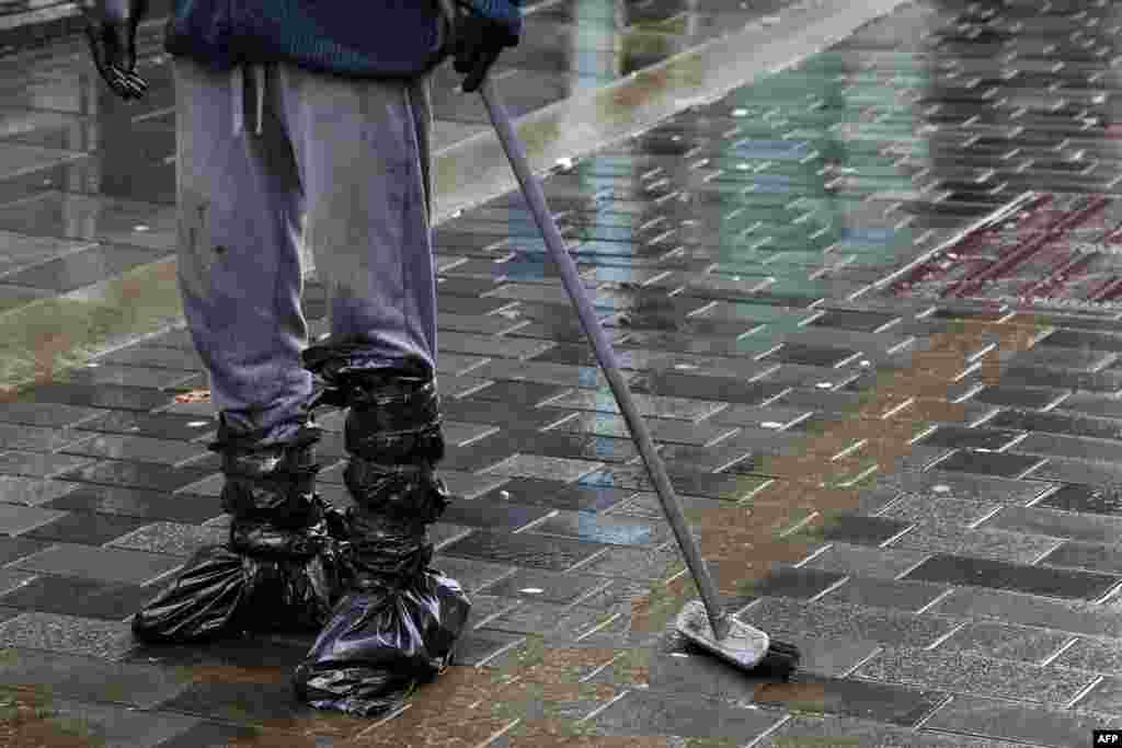 A man cleans mud from the street in Pontypridd in south Wales as Storm Dennis causes flooding across large swathes of Britain.