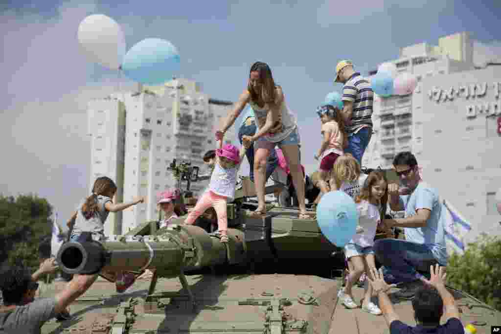 کودکان و والدین شان روی تانکی که به مناسبت شصت و نهمین سالگرد تاسیس کشور اسرائیل در تل آویو به نمایش گذاشته شد.