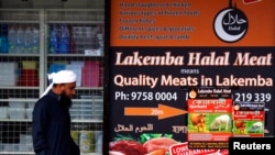 FILE - A man walks past a shop selling 'Halal meat' in the western Sydney suburb of Lakemba.