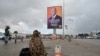 Un résident passe devant l'affiche de campagne du président sortant de la Côte d'Ivoire, Alassane Ouattara, dans une rue d'Abidjan le 15 octobre 2020.