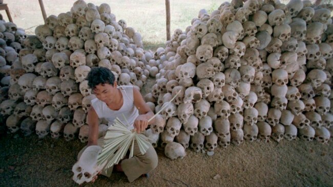 FILE - A man cleans a skull near a mass grave at the Chaung Ek torture camp run by the Khmer Rouge in this undated photo. The last surviving leaders of the Khmer Rouge regime were convicted of genocide, crimes against humanity and war crimes Nov. 16 by an international tribunal.