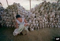 FILE - A person cleans a skull near a mass grave at the Chaung Ek torture camp run by the Khmer Rouge in Cambodia. An international tribunal convicted the surviving leaders of the Khmer Rouge regime of genocide, crimes against humanity, and war crimes in 2018. (Undated photo).