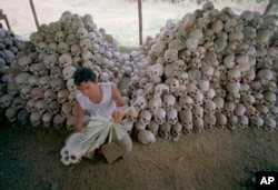 Seorang pria membersihkan tengkorak di dekat kuburan massal di kamp penyiksaan Chaung Ek yang dikelola oleh Khmer Merah di Kamboja. Pengadilan internasional menghukum para pemimpin Khmer Merah atas tuduhan genosida, dan kejahatan terhadap kemanusiaan tahun 2018.