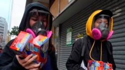 Citizens wearing full mask respirators carry packets of disposable face masks in Hong Kong, Wednesday, Feb. 5, 2020. (AP Photo/Vincent Yu)