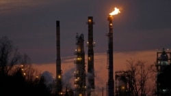 FILE - Stacks and burn-off from the ExxonMobil refinery are seen at dusk in St. Bernard Parish, Louisiana, Feb. 13, 2015.