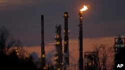 FILE - Stacks and burn-off from the ExxonMobil refinery are seen at dusk in St. Bernard Parish, Louisiana, Feb. 13, 2015.