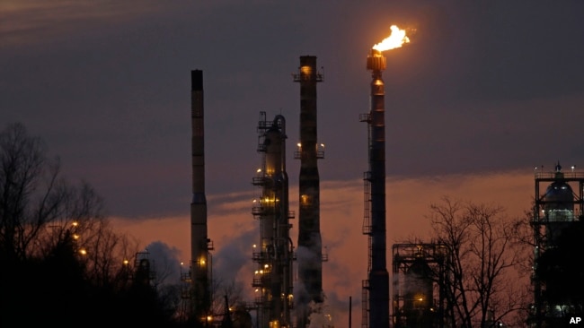 FILE - Stacks and burn-off from the ExxonMobil refinery are seen at dusk in St. Bernard Parish, Louisiana, Feb. 13, 2015.