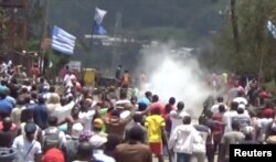 FILE - A still image taken from a video shot on Oct. 1, 2017, shows protesters waving Ambazonian flags as they move forward towards barricades and police amid tear gas in the English-speaking city of Bamenda, Cameroon.