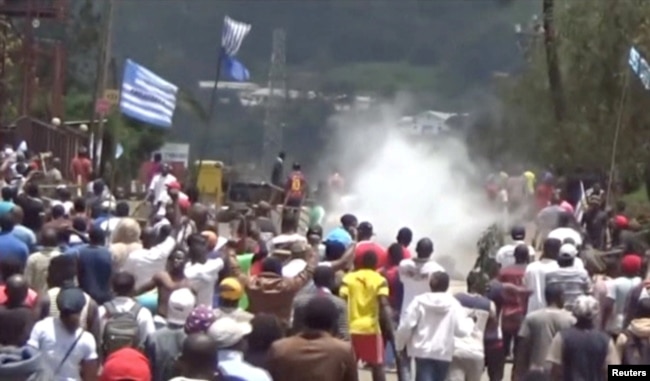 FILE - A still image taken from a video shot on Oct. 1, 2017, shows protesters waving Ambazonian flags as they move forward towards barricades and police amid tear gas in the English-speaking city of Bamenda, Cameroon.