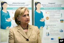 Informational Zika posters for pregnant woman are displayed behind Democratic presidential candidate Hillary Clinton as she takes a tour of Borinquen Health Care Center, in Miami, Aug. 9, 2016.
