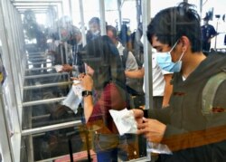 Seorang perempuan menghembuskan napas ke dalam plastik GeNose C19 untuk tes COVID-19 sebelum mudik Lebaran, di sebuah stasiun kereta di Jakarta, 5 Mei 2021. (Foto: Ajeng Dinar Ulfiana/Reuters)