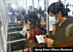 Seorang perempuan menghembuskan napas ke dalam plastik GeNose C19 untuk tes COVID-19 sebelum mudik Lebaran, di sebuah stasiun kereta di Jakarta, 5 Mei 2021. (Foto: Ajeng Dinar Ulfiana/Reuters)