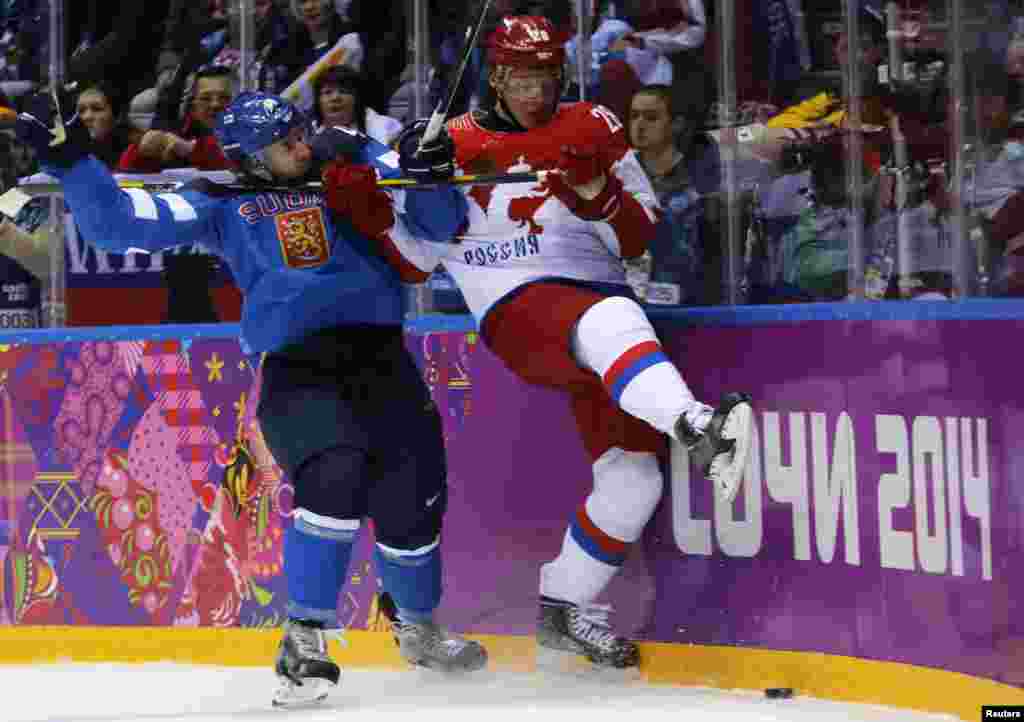 Russia's Alexander Syomin (right) and Finland's Sami Vatanen battle along the boards during the first period of the men's quarter-final ice hockey game, Sochi, Feb. 19, 2014.