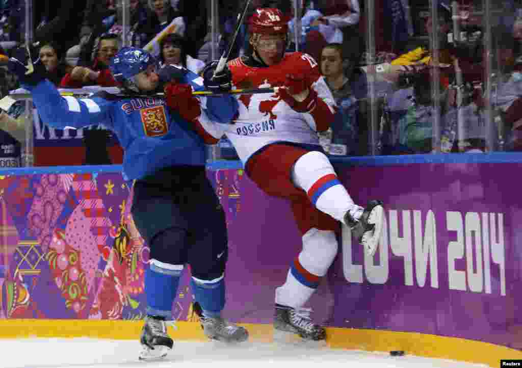 Alexander Syomin dari Rusia (kanan) dan Sami Vatanen dari Finlandia bertabrakan pada babak pertama perempat final pertandingan hoki es, Sochi, 19 Februari 2014.