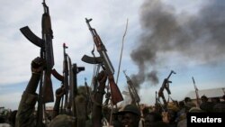 Des combattants rebelles marchent avec leurs armes en l'air dans le territoire rebelle de l'Upper Nile State, au Soudan du Sud, le 13 février 2014.