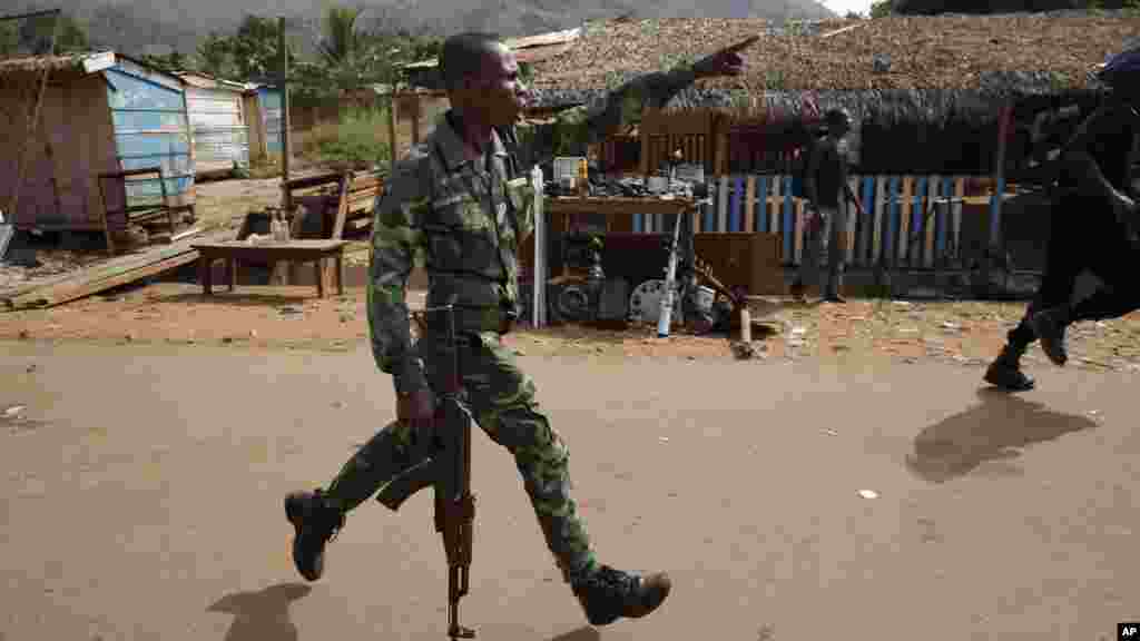 Un policier centrafricain pourchasse des pillards qui attaquent un camion en panne, alors que des milliers de résidents musulmans de Bangui et Mbaiki fuient la violence à Bangui, 7 février 2014. (AP Photo / Jerome Delay)