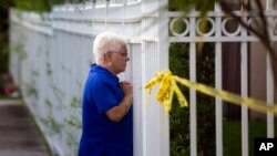 Una mujer mira a través de la valla que cerca la casa donde sucedió el asesinato. 