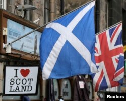 FILE - The Scottish Saltire flag (L) and the British Union flag are seen outside a shop in the centre of Edinburgh, Scotland on Sept. 12, 2014.