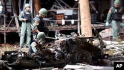 FILE - Thai bomb squad officers examine the wreckage of a car after an explosion outside a hotel in Pattani province, southern Thailand, Aug. 24, 2016.