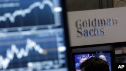 FILE - A screen at a trading post on the floor of the New York Stock Exchange is juxtaposed with the Goldman Sachs booth, Oct. 16, 2014.