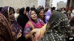 Pakistani women mourn the death of a relative killed from a fire in a factory in Karachi, Pakistan, September 13, 2012. 