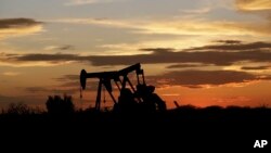 Pompa angguk di sebuah lapangan minyak saat matahari terbenam, di Karnes City, Texas, Amerika Serikat, 5 Juni 2017.