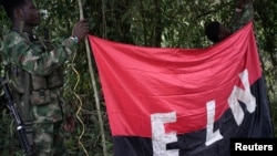 FILE - Rebels of the National Liberation Army (ELN) hold a banner in the northwestern jungles in Colombia, Aug. 30, 2017. 