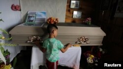 A child touches the coffin of Nelson Espinal, 28, Dec. 19, 2018. Espinal was shot to death the night before shortly after leaving his home in Tegucigalpa, Honduras.