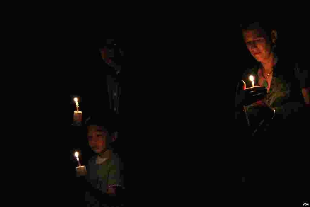 Rachel Chung (right), her husband Sambath Chung (lelft) and son Sorya Chung, take part in a candle vigil around the main temple during a memorial service for Khmer Rouge victims at the Wat Buddhikaram Cambodian Buddhist temple in Silver Spring, Maryland, to mark the 40th anniversary of the takeover of the Khmer Rouge, on Friday, April 17, 2015. (Sophat Soeung/VOA Khmer)