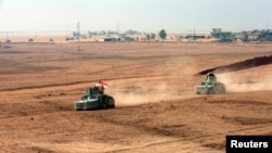 Kurdish peshmerga fighters drive vehicles at the front line during a battle with Islamic State militants at Topzawa village near Bashiqa, Iraq, Oct. 24, 2016. 