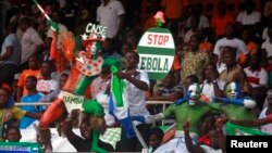 Penonton berkostum membawa papan bertuliskan "Stop Ebola" dalam pertandingan kualifikasi Piala Afrika 2015 antara Pantai Gading dan Sierra Leone di stadion Felix Houphouet Boigny di Abidjan, September 2014. (Reuters/Luc Gnago)