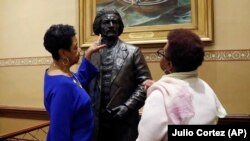 Joyce Amos, left, and Pamela Johnson, who both work in the office of Maryland House Speaker Adrienne Jones, inspect a bronze statue of abolitionist Frederick Douglass during a private viewing ahead of its unveiling at the Maryland State House, Monday, Feb