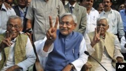 Bihar state Chief Minister Nitish Kumar, center, displays the victory sign during a press conference after his National Democratic Alliance won the state elections, in Patna, India, Nov. 24, 2010. Kumar, the top elected official of one of India's poorest 