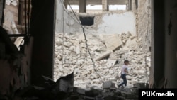 A child walks past damaged buildings after an airstrike in the rebel-held area of Aleppo's Baedeen district, Syria, May 3, 2016.