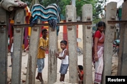 Children play as a woman crosses a railway fence at a slum area in New Delhi, India, July 11, 2018.