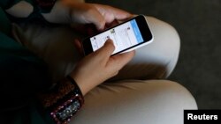 FILE - Farah Baker, 16, uses her phone to tweet her family. California approved a new 'kill switch' law in an effort to deter rampant theft of mobile devices, August 10, 2014.