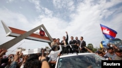 President of the Cambodia National Rescue Party Sam Rainsy (C) speaks to supporters over a loudspeaker, after arriving at Phnom Penh International Airport in Phnom Penh, July 19, 2014.