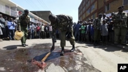 Kenyan police officers clean the scene where a police van was attacked at the Eastleigh neighbourhood in the capital Nairobi, 03 Dec 2010