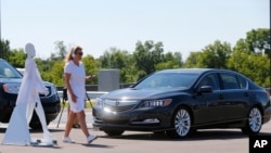 FILE - A pedestrian crosses in front of a vehicle as part of a demonstration at the Mcity test facility at the University of Michigan in Ann Arbor, July 20, 2016. Automakers say cars that wirelessly talk to each other hold the potential to dramatically reduce traffic deaths.