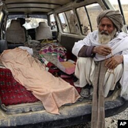An elderly Afghan man sits in a minivan next to the covered body of a person allegedly shot dead by a U.S. service member in Panjwai, Kandahar province, Afghanistan, March 11, 2012.